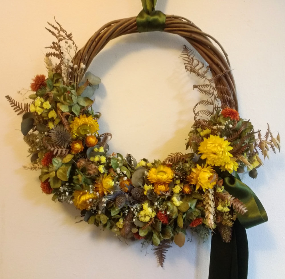 A handmade Willow Wreath trimmed with dried flowers in yellows, orange & rusts for Autumn. Copyright www.GallowayFlowers.co.uk