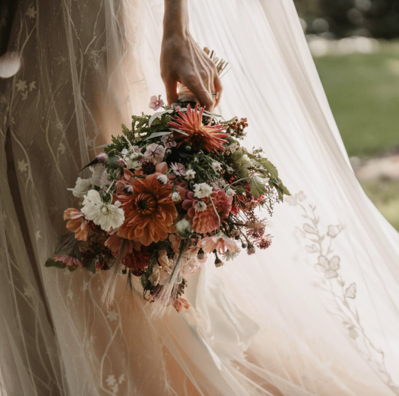 Bride in wedding dress with bridal bouquet in peach & Caramel colours at a September wedding. Photo credit Willow&Wilde.co